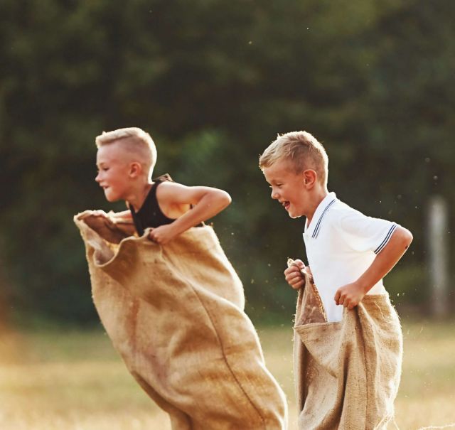 2 Jungen sind auf einer Wiese und machen Sackhüpfen