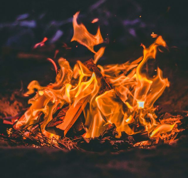 Auf schwarzem Hintergrund, ein Lagerfeuer mit lodernden Flammen.