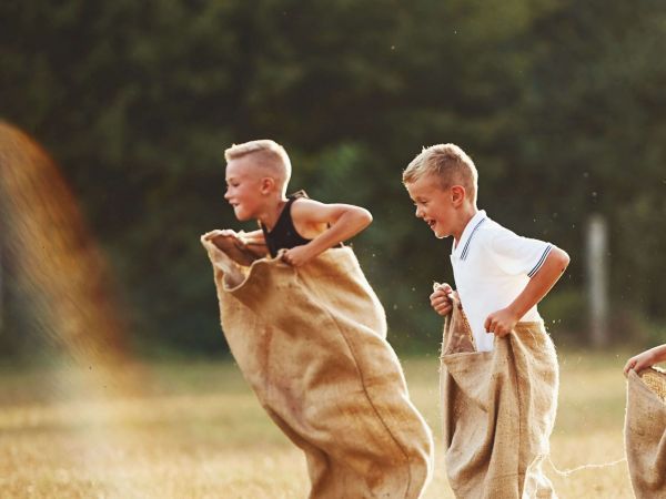 2 Jungen sind auf einer Wiese und machen Sackhüpfen